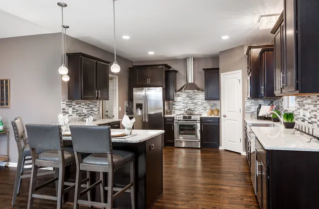 a kitchen with stainless steel appliances kitchen island granite countertop a stove top oven a sink a dining table and chairs with wooden floor