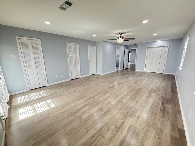 a view of empty room with wooden floor and fan