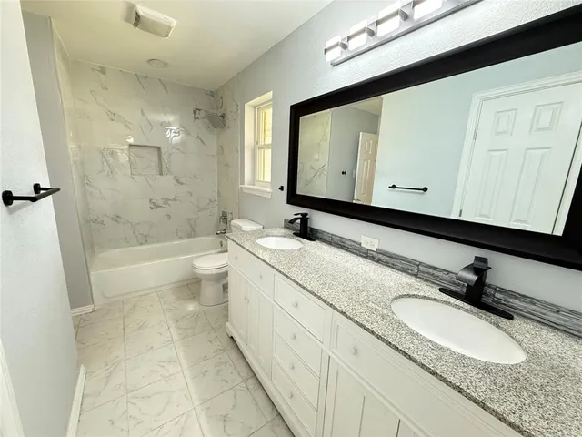 a bathroom with a granite countertop sink a mirror and a bathtub