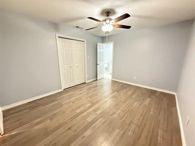 an empty room with wooden floor and a ceiling fan