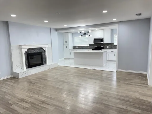 a view of kitchen with kitchen island a sink wooden floor and a refrigerator