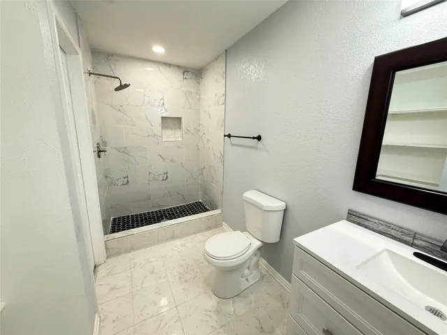 a bathroom with a sink a toilet a glass door shower and a mirror