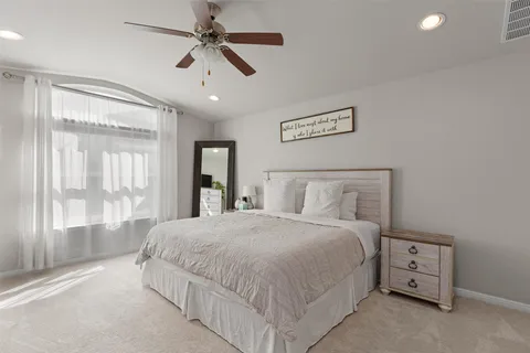 a bedroom with a large bed and a chandelier fan