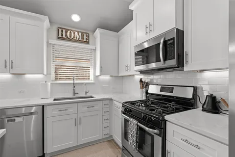 a kitchen with stainless steel appliances white cabinets and a stove top oven