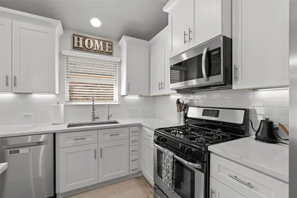 a kitchen with stainless steel appliances white cabinets and a stove top oven