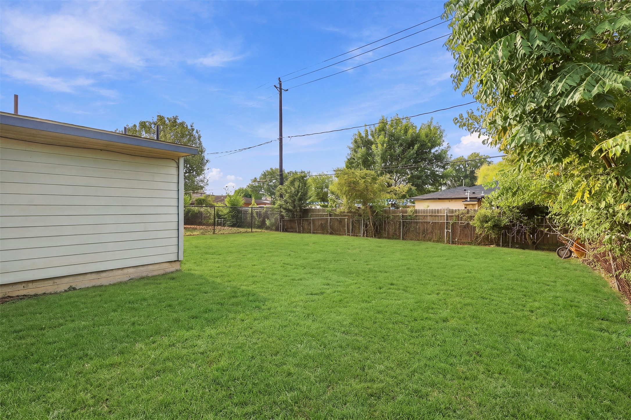 4926 Edfield Street Houston, TX 77033 - Photo 21 of 30 Expansive backyard with lush green lawn, perfect for outdoor activities and relaxation, bordered by mature trees for added privacy.