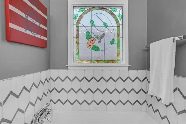 a white painted wall with a white comforter and a painting on the wall