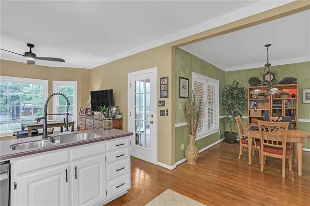 a kitchen with stainless steel appliances a dining table chairs and wooden floor