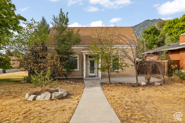 View of front of home featuring roof with shingles, a mountain view, and stucco siding
