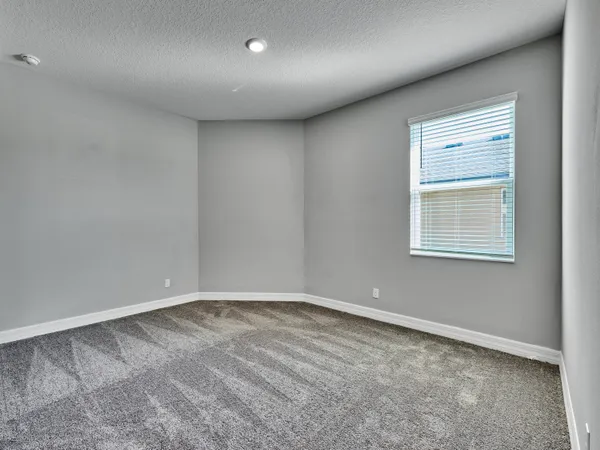 a view of an empty room with wooden floor and a ceiling fan