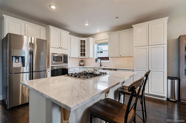 a kitchen with stainless steel appliances a refrigerator a stove a sink a table and chairs
