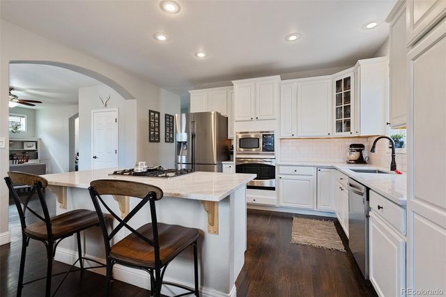 a kitchen with stainless steel appliances kitchen island granite countertop a table chairs sink and cabinets