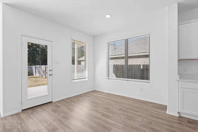 an empty room with wooden floor and windows