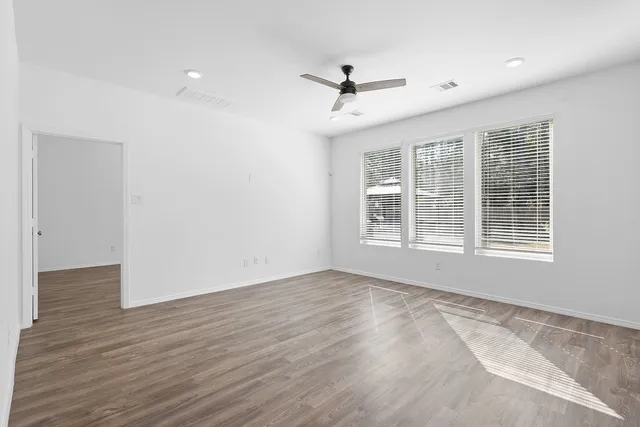 a view of an empty room with wooden floor and a window