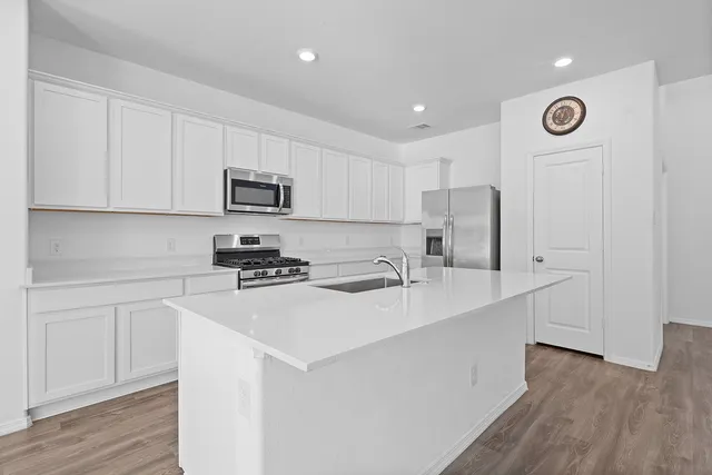 a kitchen with stainless steel appliances a stove a sink a refrigerator and cabinets