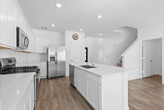 a kitchen with a sink a refrigerator and a stove top oven