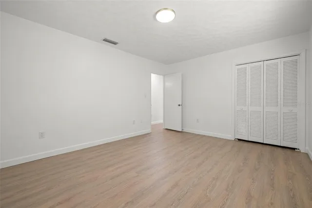 a view of an empty room with wooden floor and entryway