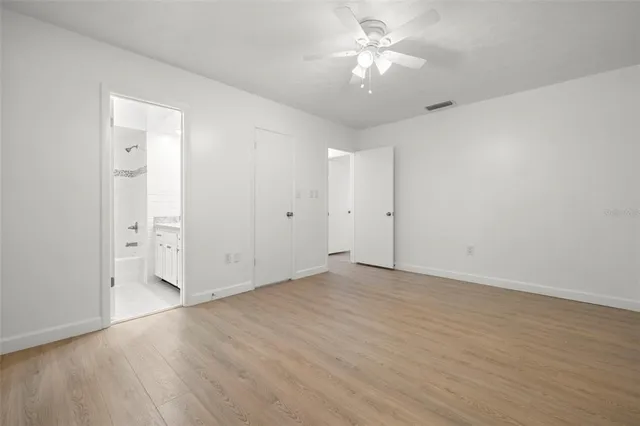 an empty room with chandelier fan and windows