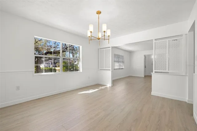 an empty room with wooden floor cabinet and windows