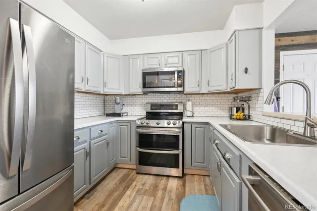 a kitchen with white cabinets sink and stainless steel appliances