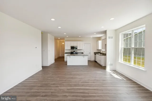 a view of kitchen with kitchen island a sink wooden floor and a refrigerator