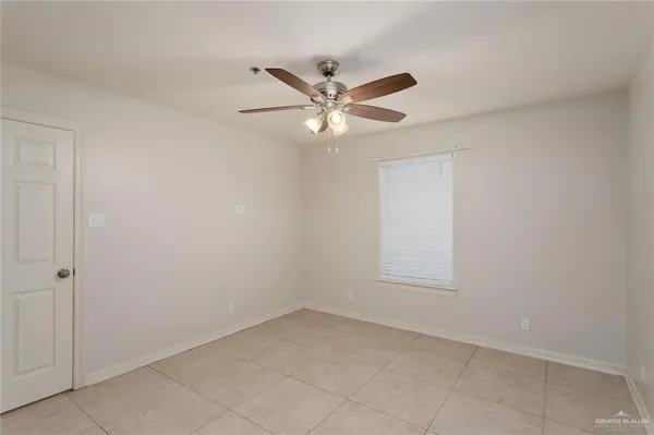 an empty room with chandelier fan and windows