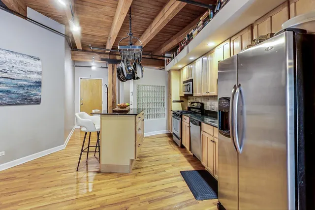 a kitchen with stainless steel appliances granite countertop a refrigerator a stove and a wooden floors