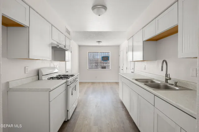 a kitchen with granite countertop a sink stove and cabinets