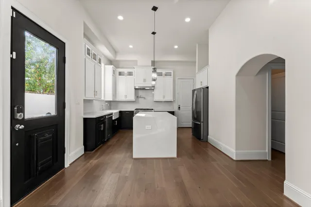 a kitchen with kitchen island wooden floors appliances and cabinets