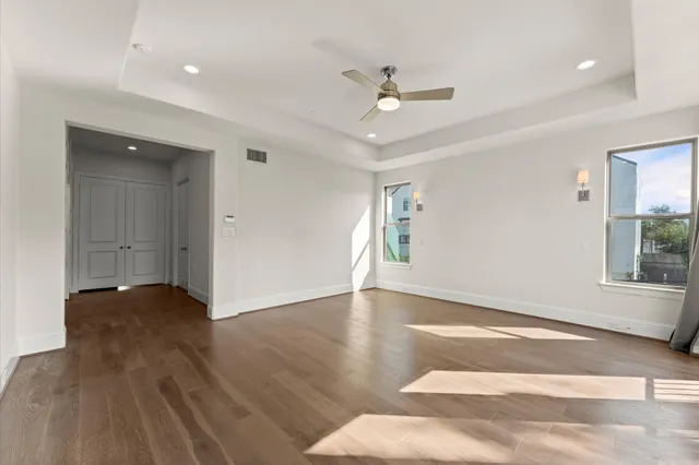 a view of an empty room with wooden floor and a window
