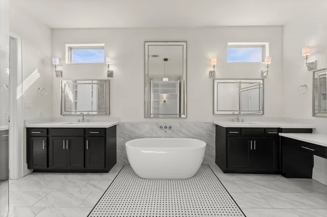 a spacious bathroom with a tub double sink and mirror