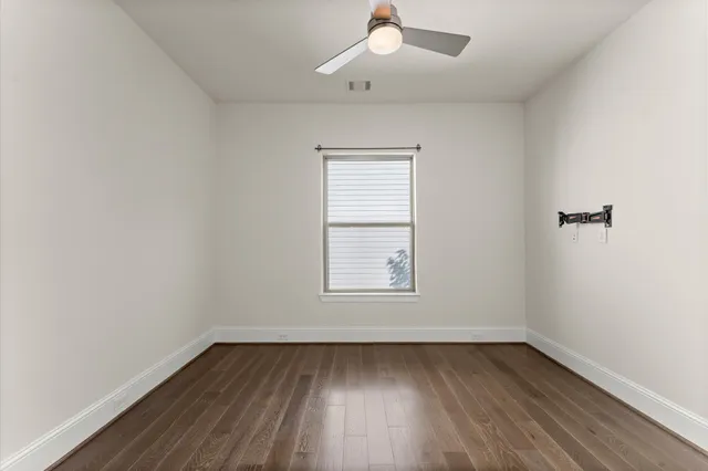 an empty room with wooden floor ceiling fan and windows