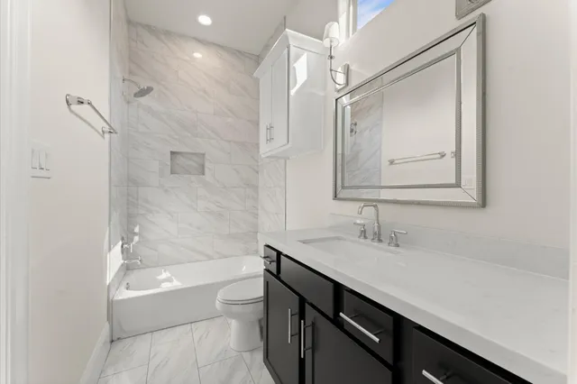 a bathroom with a bathtub shower sink vanity and toilet