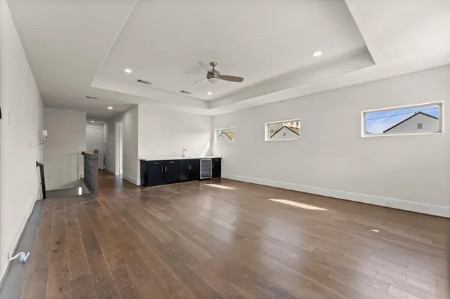 a view of an empty room with wooden floor and a ceiling fan