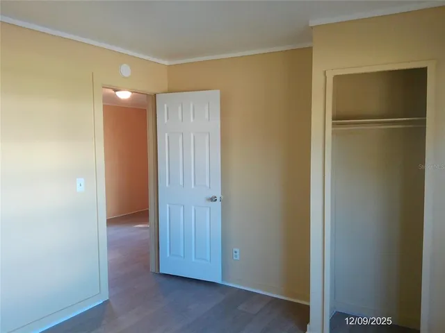 a view of an empty room with wooden floor and closet