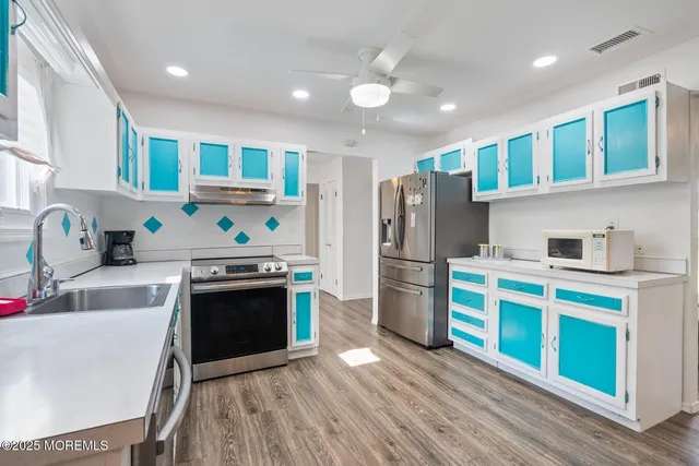 a kitchen with stainless steel appliances granite countertop a dining table chairs stove refrigerator and cabinets