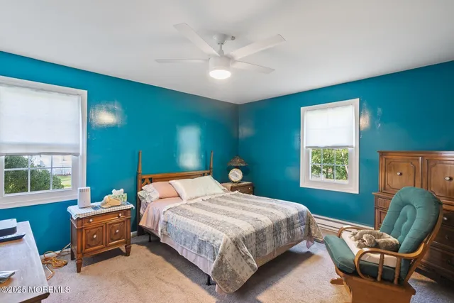 a bedroom with a bed and dresser with exposed radiator
