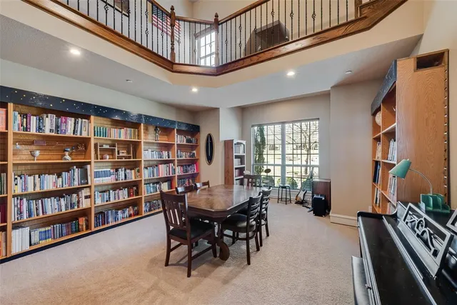 a dining hall with stainless steel appliances kitchen island granite countertop a table chairs and a sink