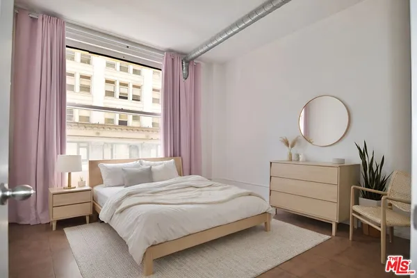 a bedroom with a bed a mirror and a window