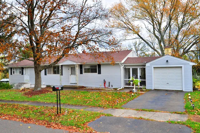 a front view of a house with a yard and large tree