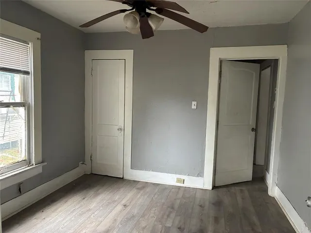 an empty room with wooden floor cabinet and windows
