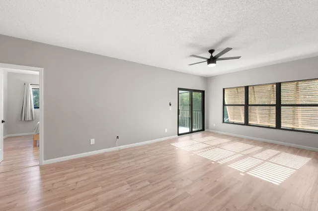 a view of an empty room with a window and wooden floor