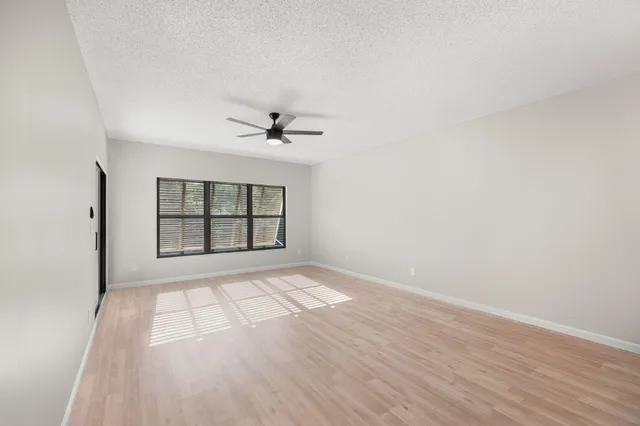 a view of an empty room with a window and wooden floor