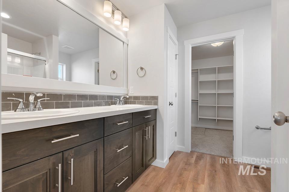 1340 Dawn Street Weiser, ID 83672 - Photo 16 of 32 Bathroom with double vanity, light wood-style flooring, backsplash, a spacious closet, and a stall shower