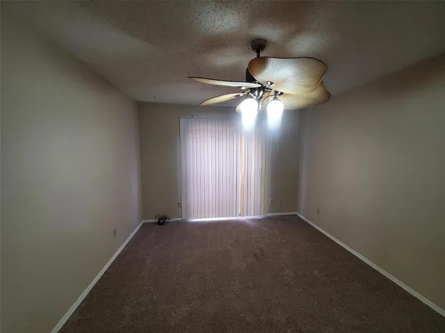 an empty room with a ceiling fan and window