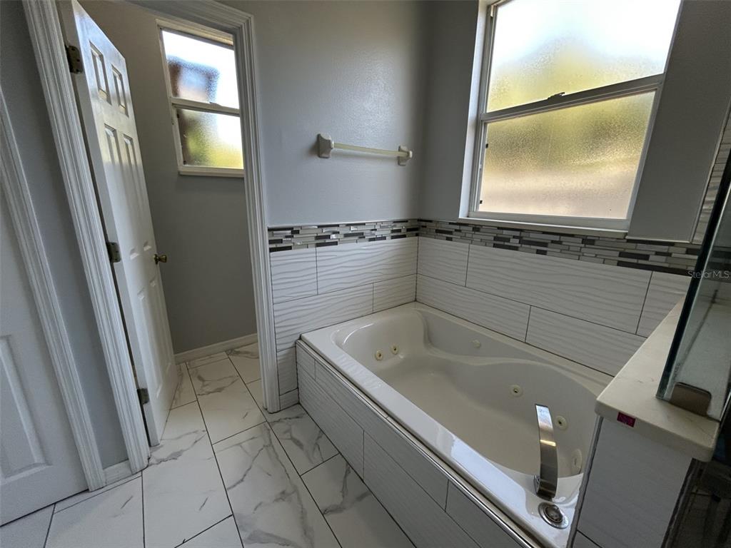 10439 Andover Point Circle Orlando, FL 32825 - Photo 23 of 33 a bathroom with a tub a mirror and a shower
