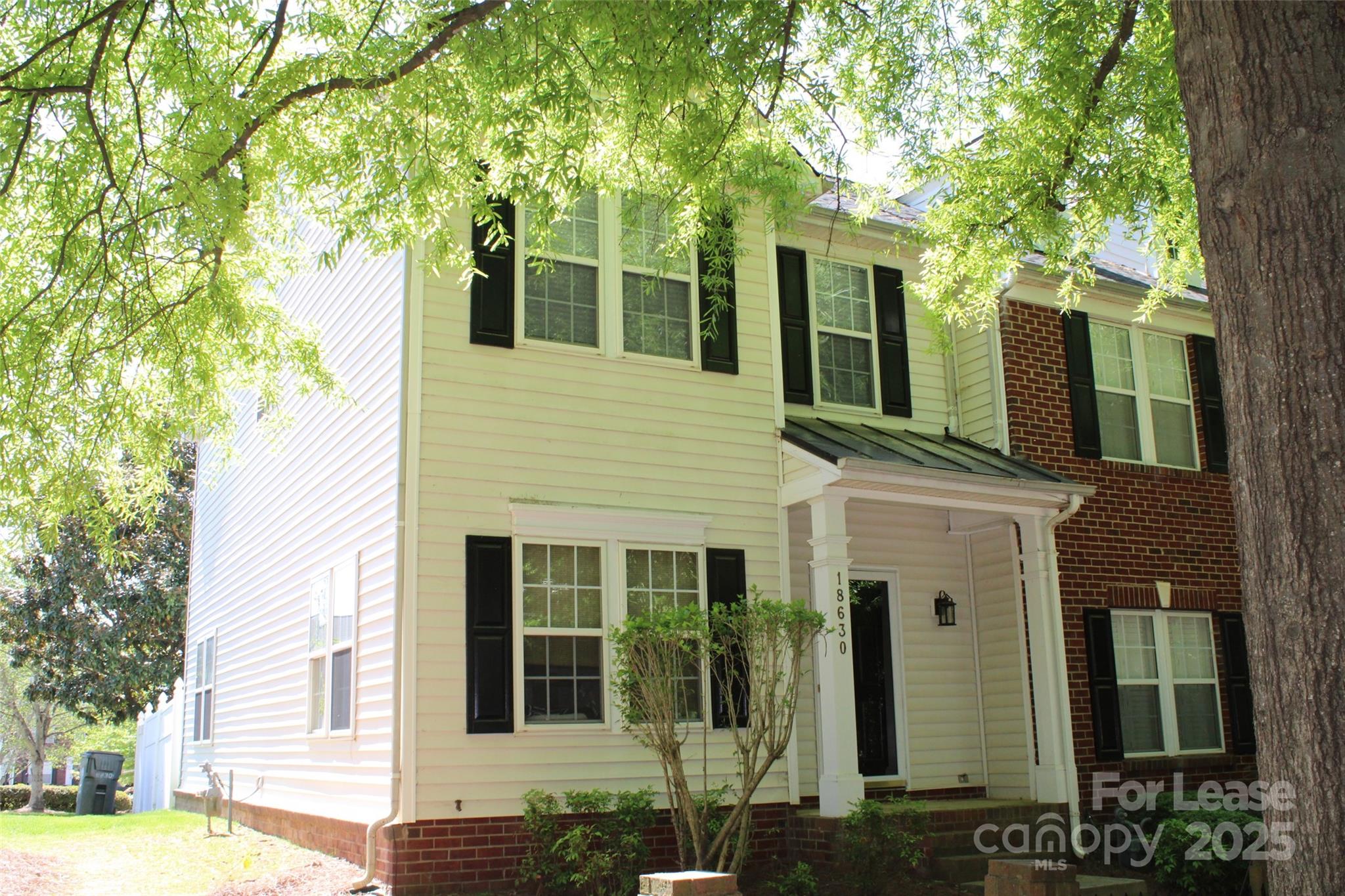 18630 Oakhurst Boulevard Cornelius, NC 28031 - Photo 1 of 20 a view of a brick house with large windows and a large tree
