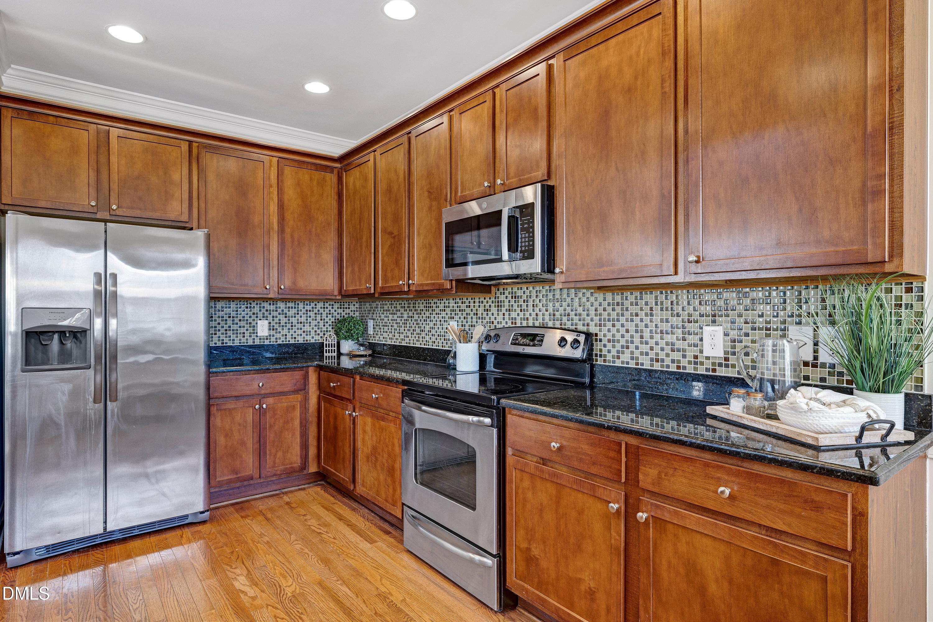 678 Democracy Street Raleigh, NC 27603 - Photo 19 of 67 a kitchen with stainless steel appliances granite countertop a stove a sink dishwasher a refrigerator and cabinets with wooden floor