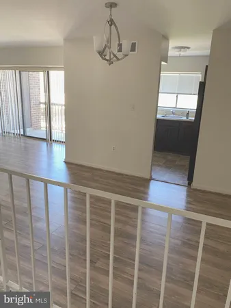 a view of an empty room with wooden floor and windows