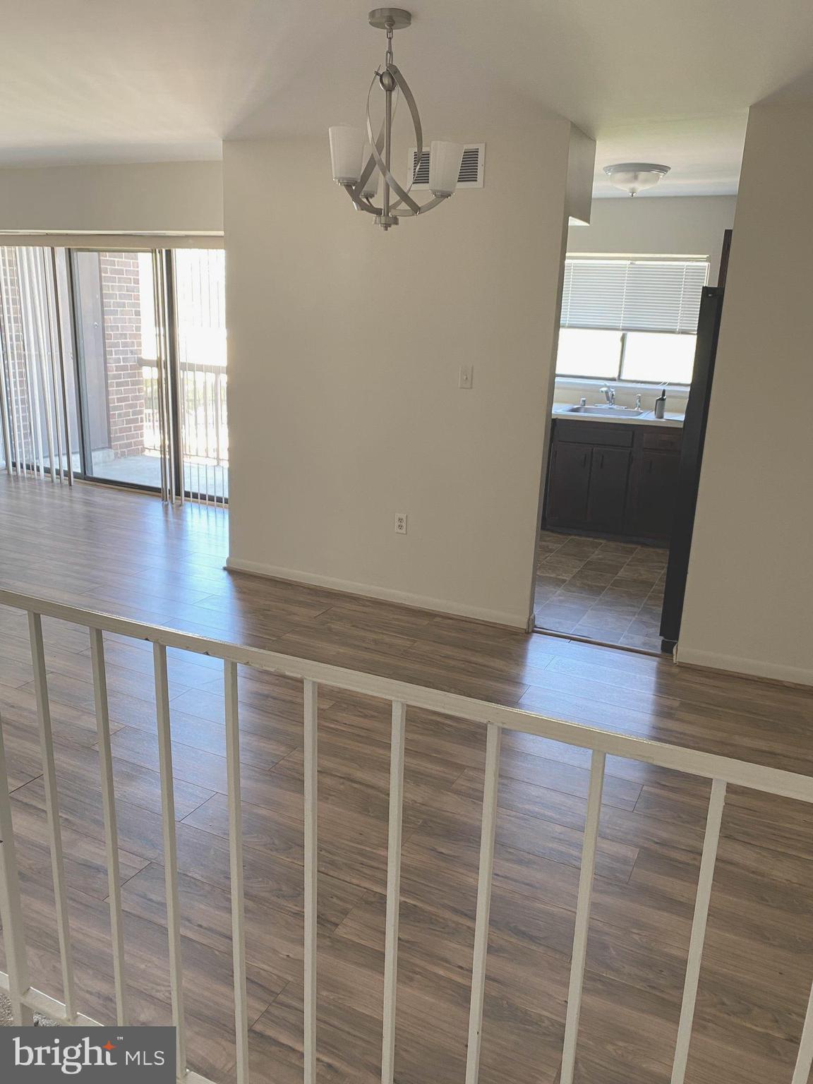 a view of an empty room with wooden floor and windows